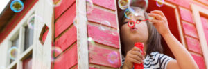 young girl blowing bubbles outside of treehouse